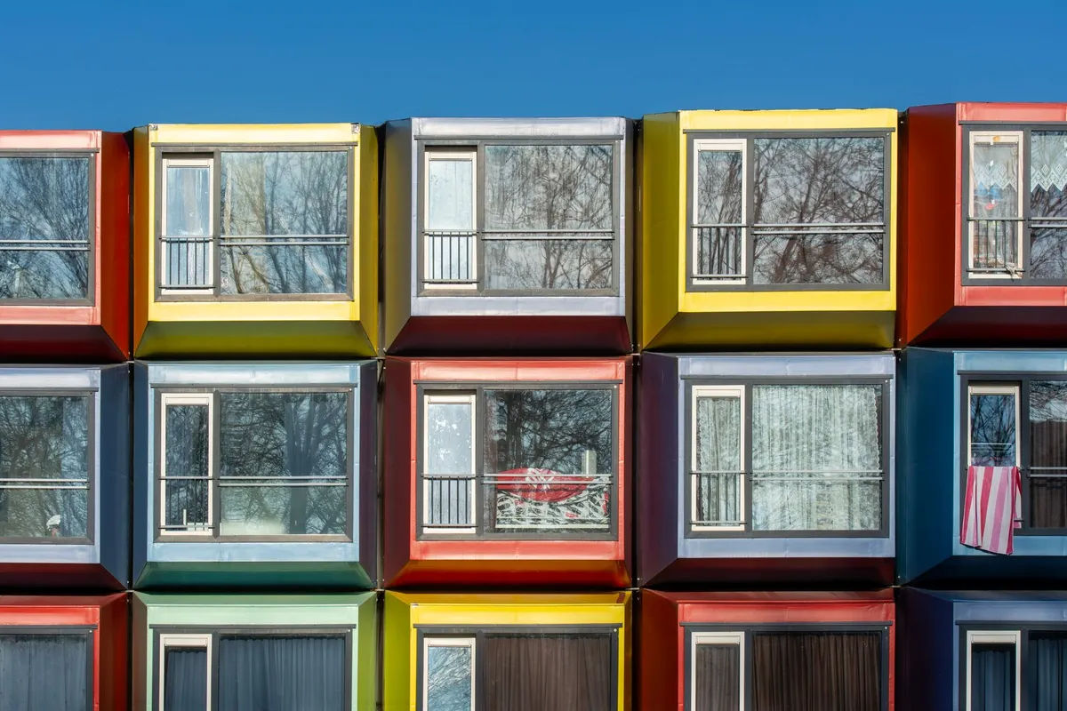 Close-up of vibrant modular apartment windows reflecting winter trees.