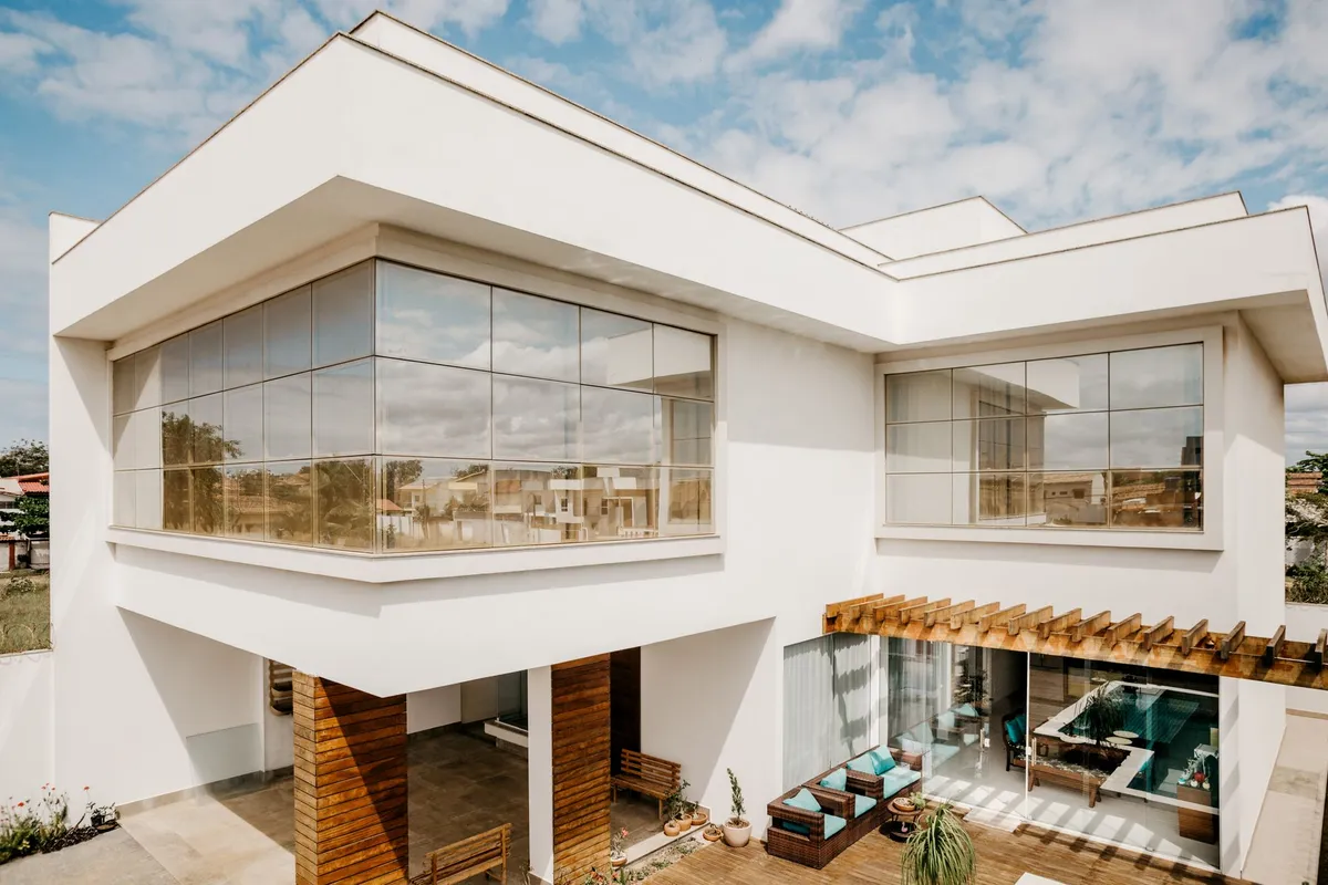 Exterior of contemporary cottage with large windows and stylish terrace against cloudy blue sky